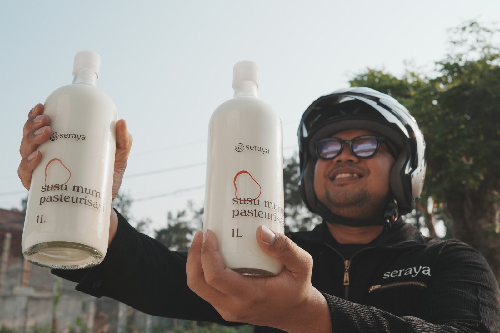 Pengantar membawa dua botol kaca susu murni pasteurisasi Seraya 1 liter